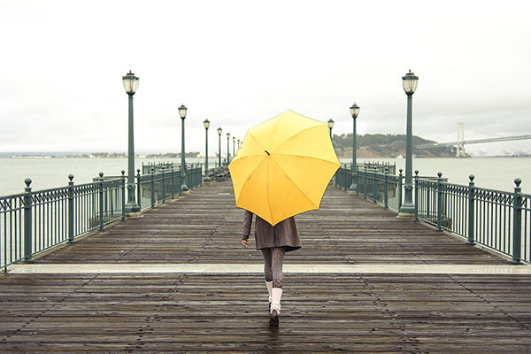 Pretty African American girl walking with umbrella on the pier in San Francisco