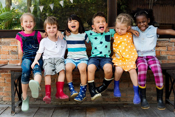 Kindergarten kids friends arm around sitting smiling